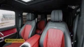 2026 Mercedes-Benz G-Class MBS Edition front passenger interior view showing the custom red and black quilted leather bucket seat, center armrest, and starlight headliner