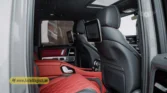 2026 Mercedes-Benz G-Class MBS Edition rear-passenger interior view highlighting the custom red and black quilted leather seats, entertainment screens mounted on the front headrests, and starlight headliner