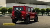 2026 Suzuki Jimny GLX 5-Door AT rear exterior view in red with alloy wheels and spare tire mounted on the tailgate